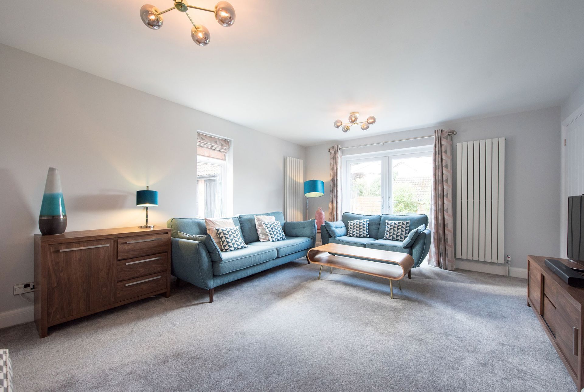 Living room with two blue sofas, wooden furniture, and gray carpet.