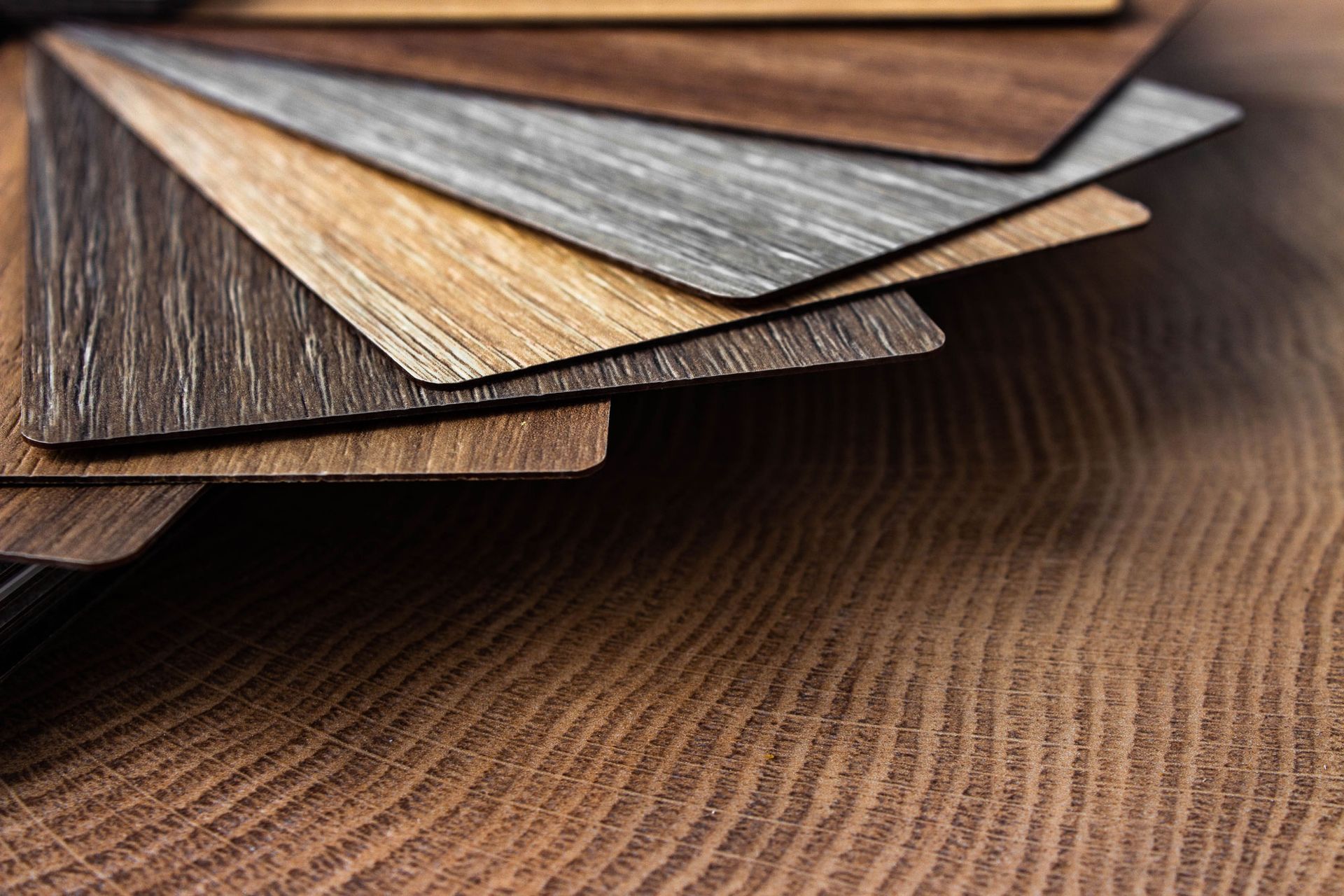 Wood grain samples fanned out over a textured wooden surface.