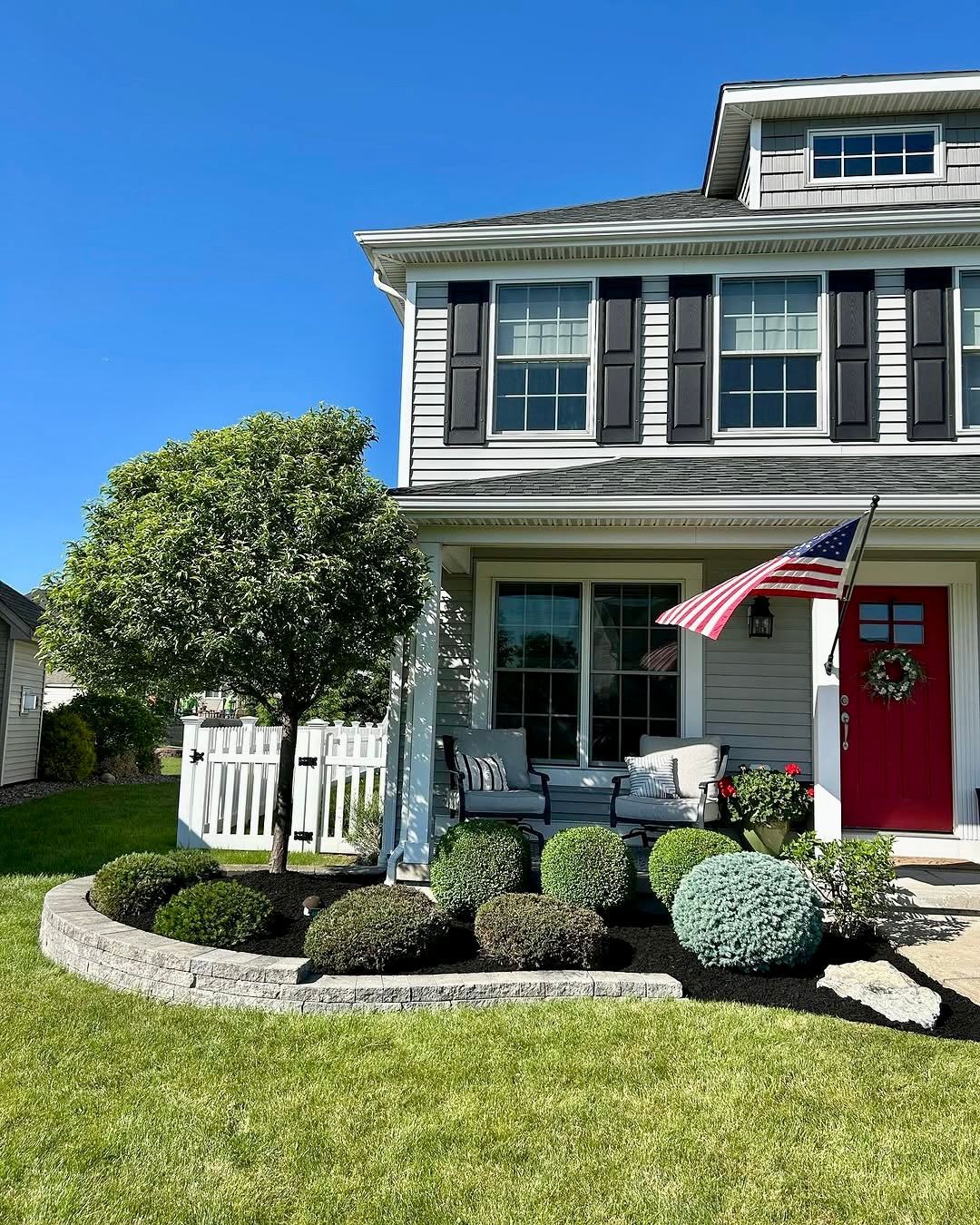 A house with a red door and an american flag on the front porch.