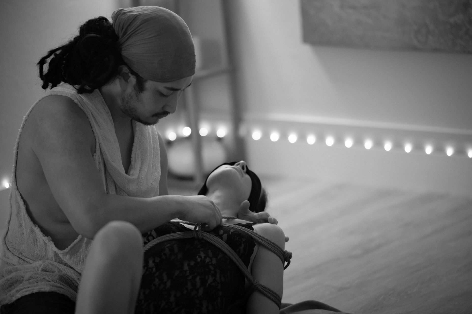 Person kneels over another in a dimly lit room.
