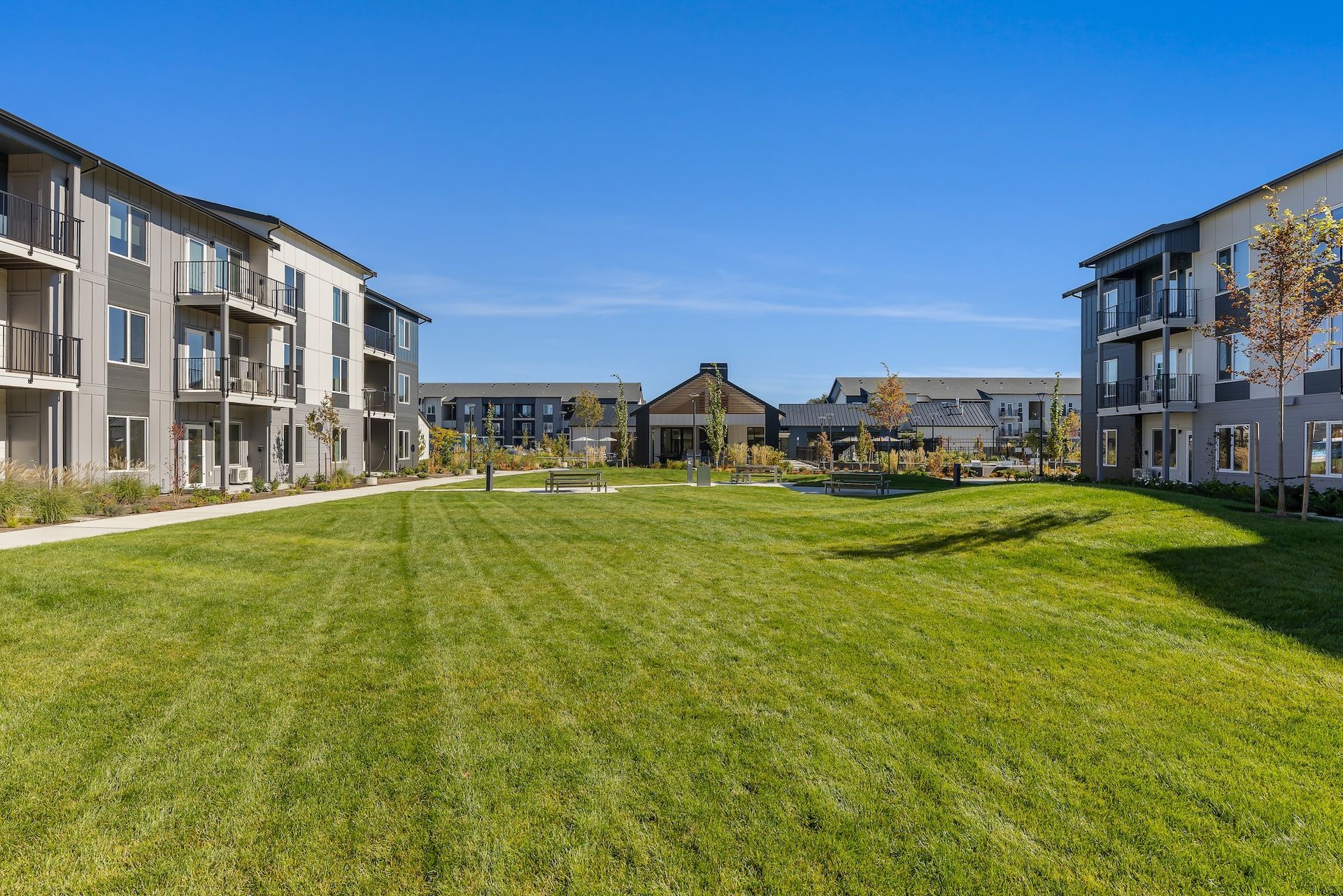 Apartment complex with a large green lawn under a clear blue sky