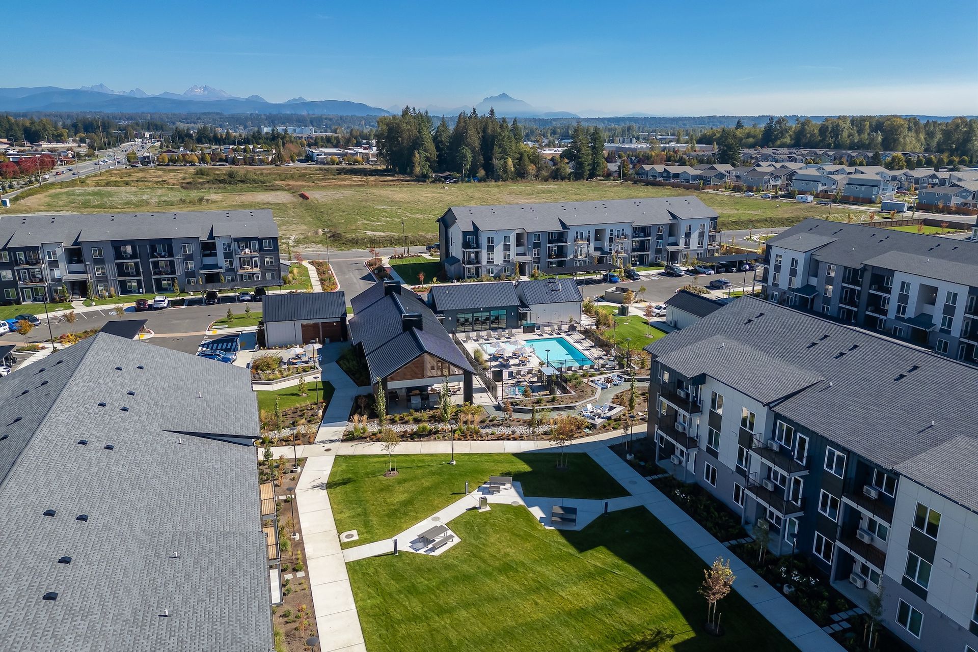 Aerial view of modern apartment buildings around a central courtyard and green lawn