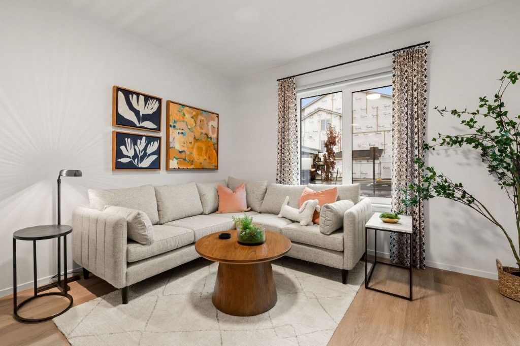 A living room with a couch , coffee table , and paintings on the wall.