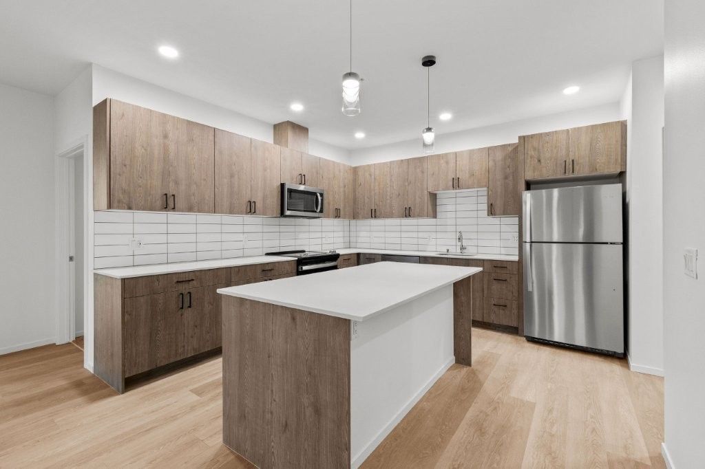 A kitchen with wooden cabinets , stainless steel appliances , and a large island.
