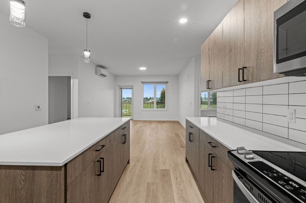 A kitchen with wooden cabinets , white counter tops , a stove , and a microwave.