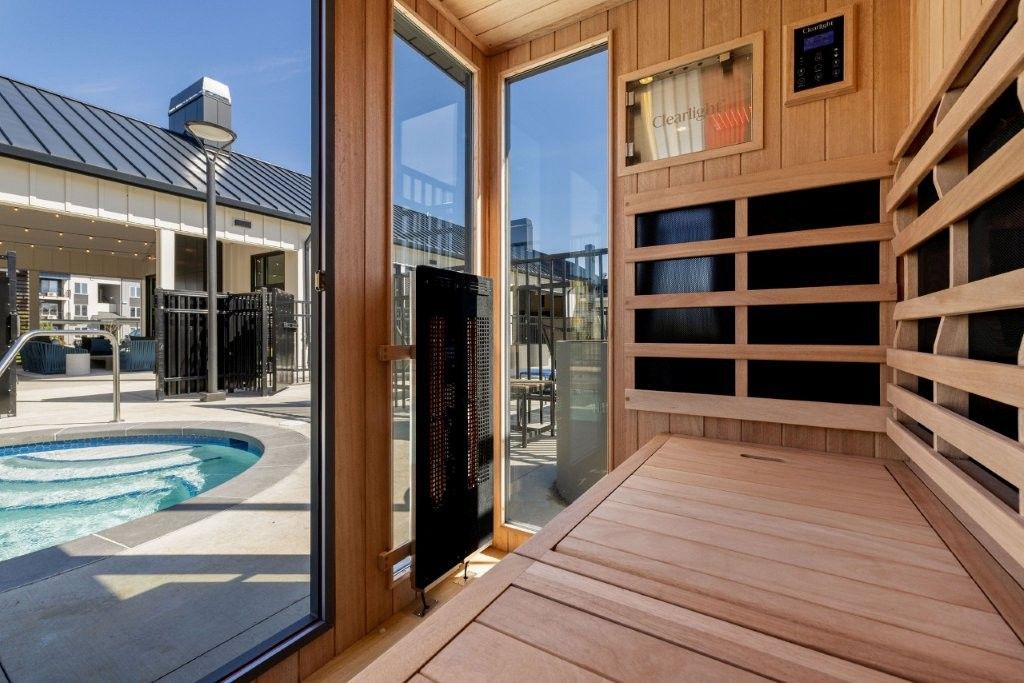 A wooden sauna with a view of a pool.