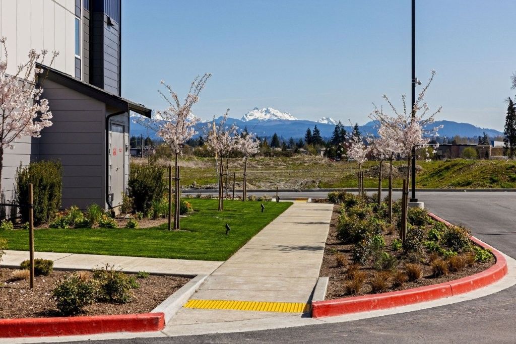 A sidewalk leading to a building with mountains in the background