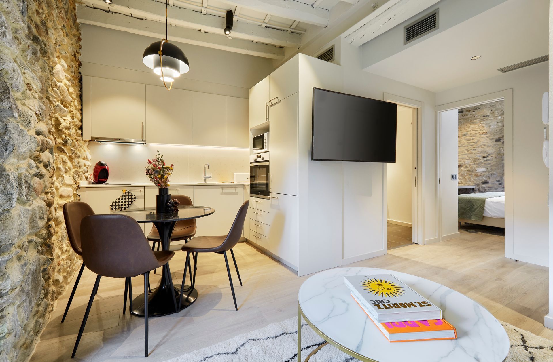 A living room with a dining table and chairs and a flat screen tv.