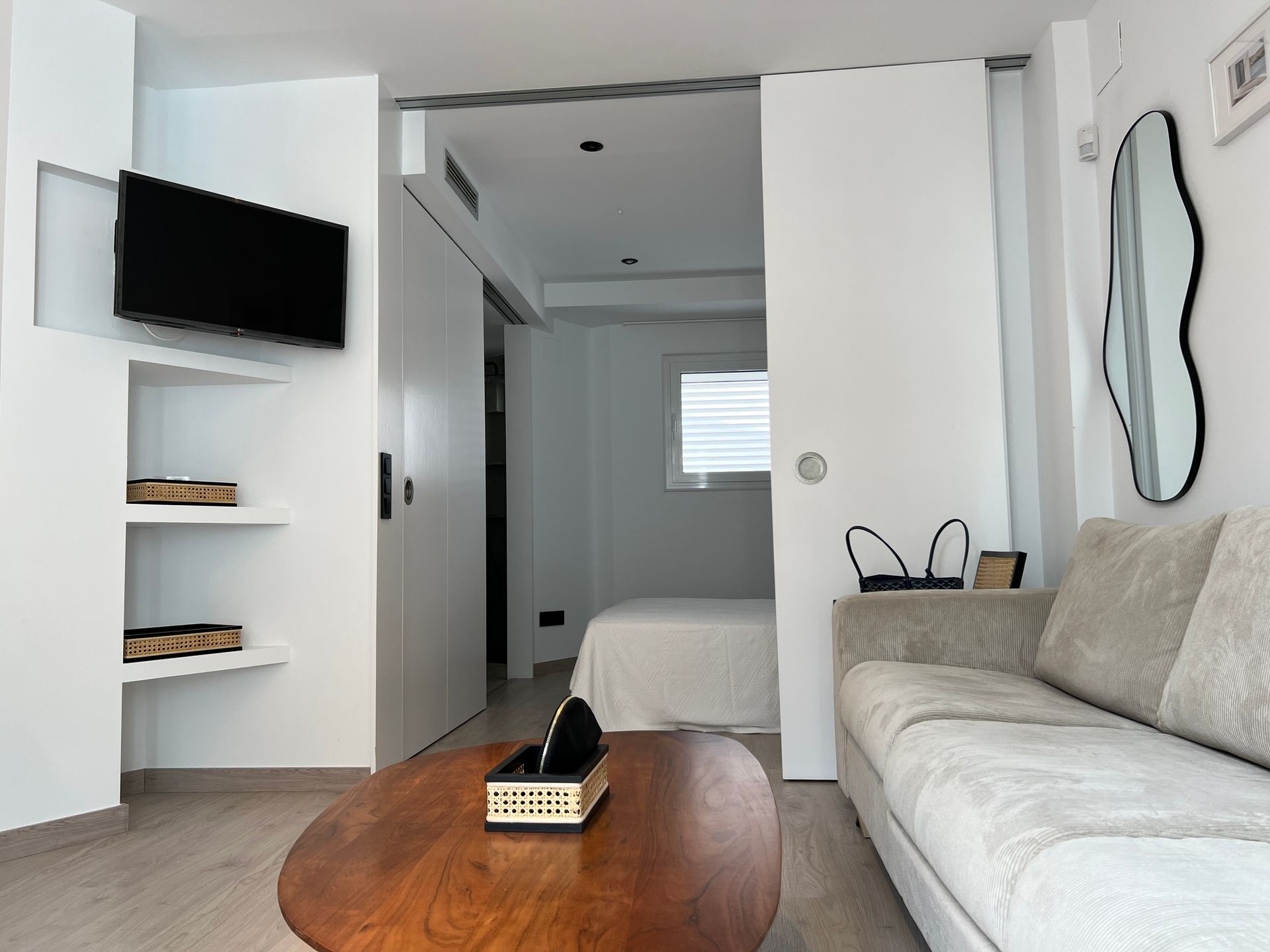 Living room with a sofa, TV, and sliding door to bedroom.