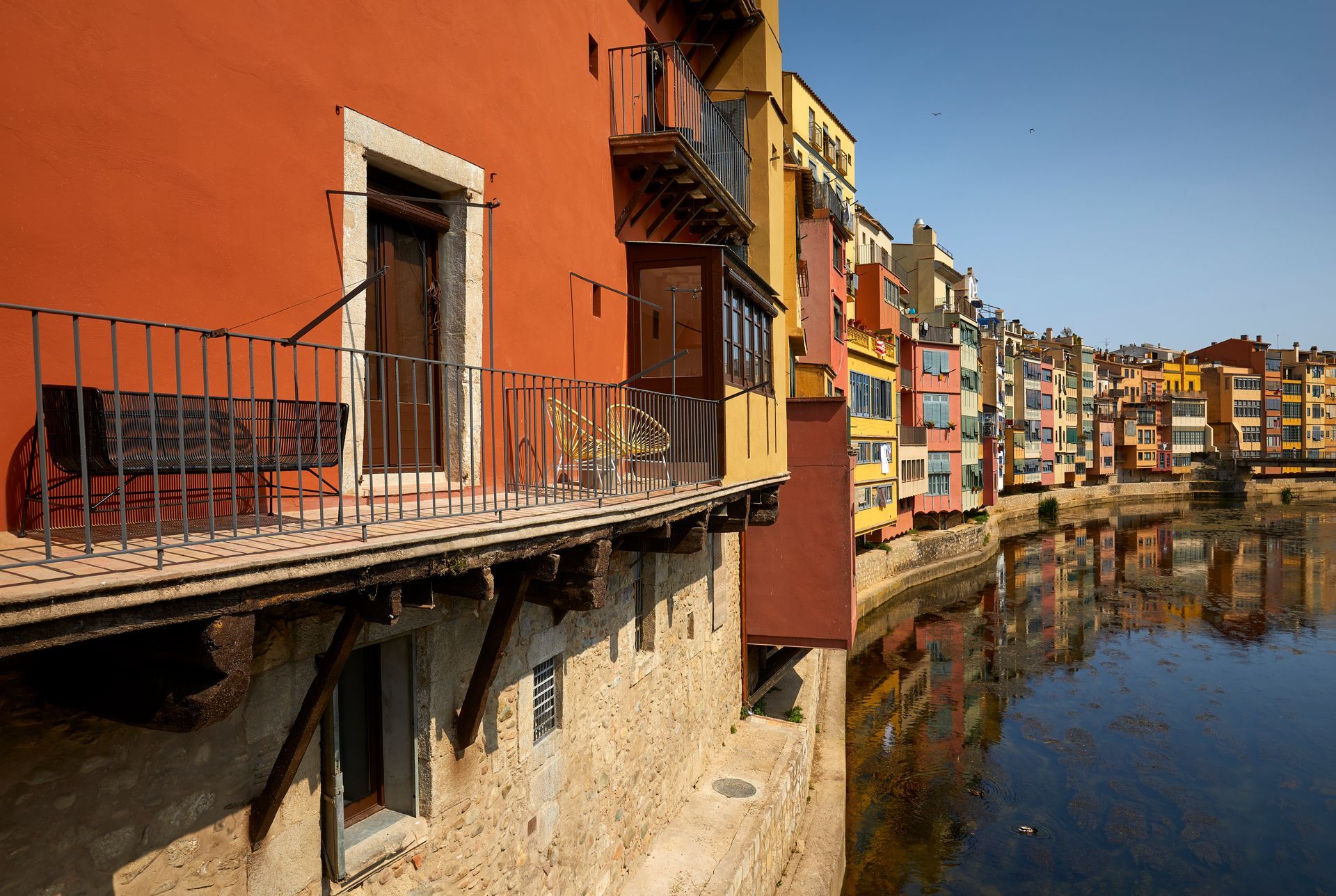 A row of buildings along a river with a balcony overlooking the water.