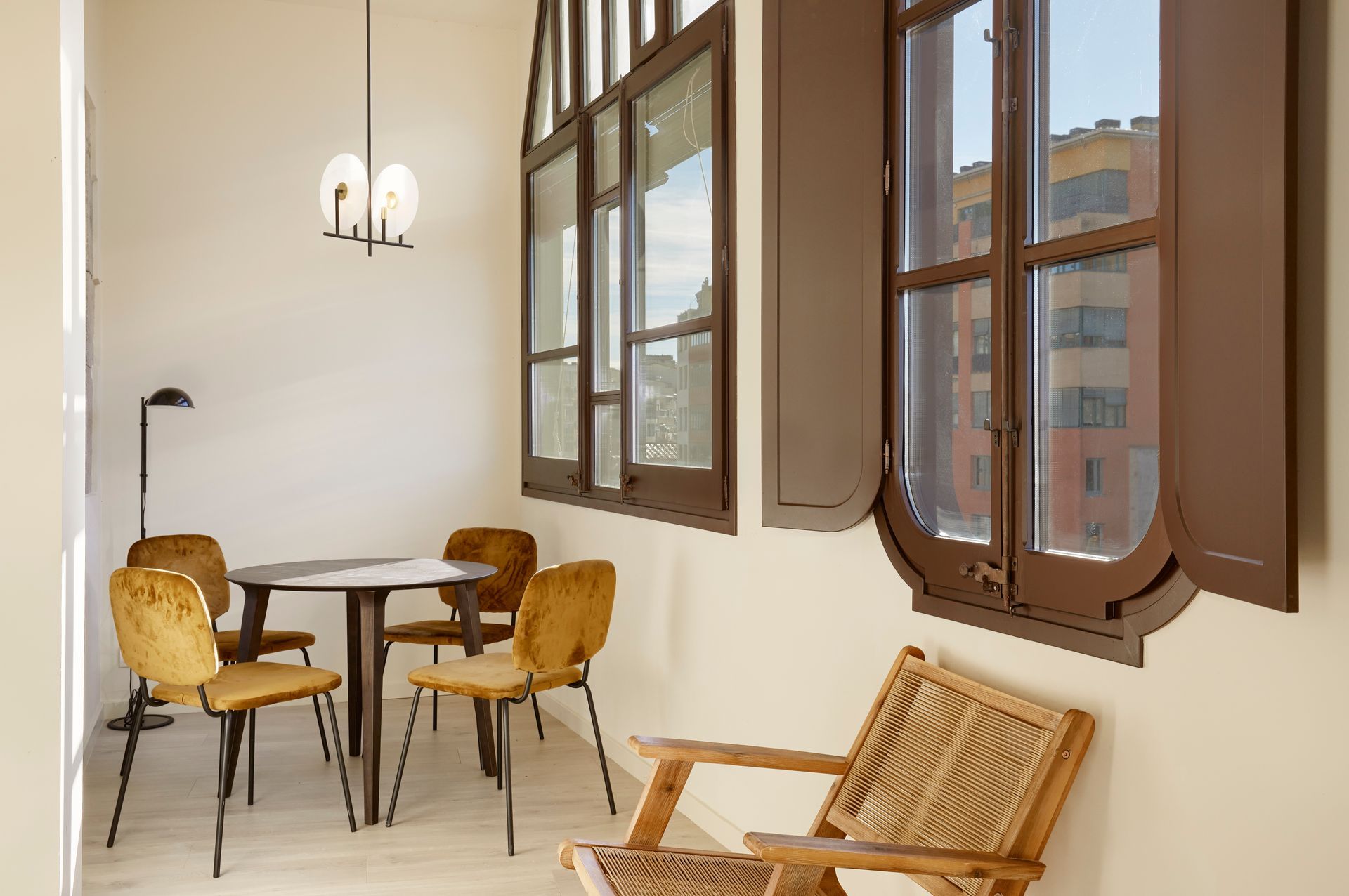 A room with a table and chairs and a chair in front of a window.