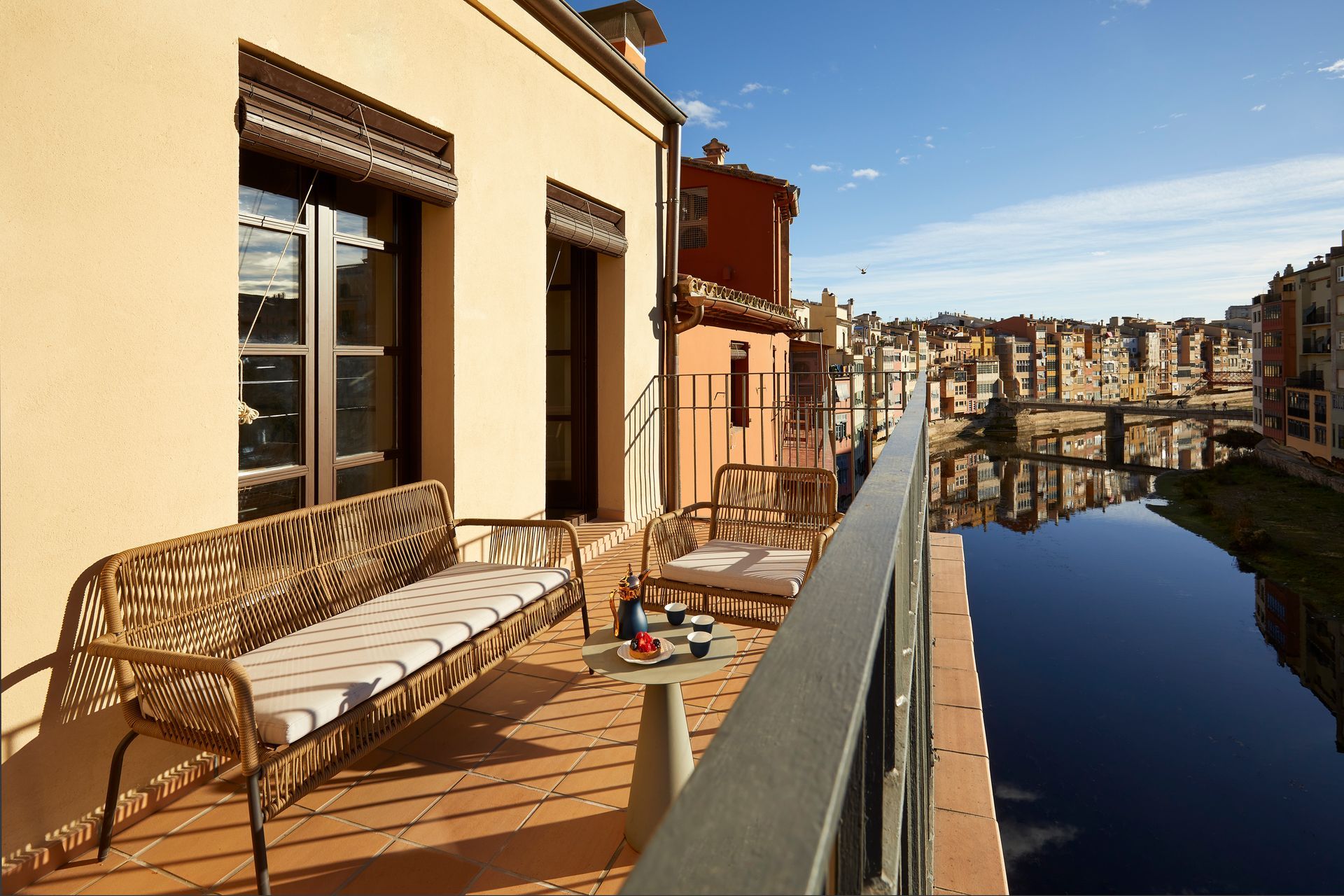 A balcony with a couch and chairs overlooking a river