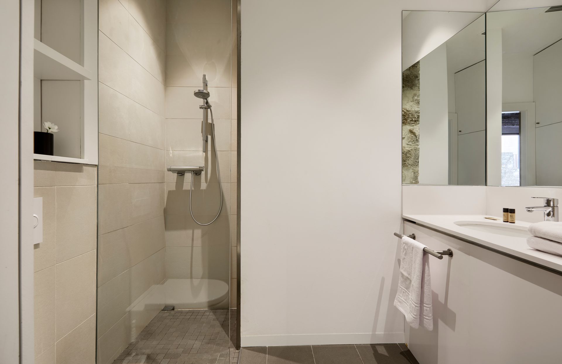 A bathroom with a walk in shower and a sink