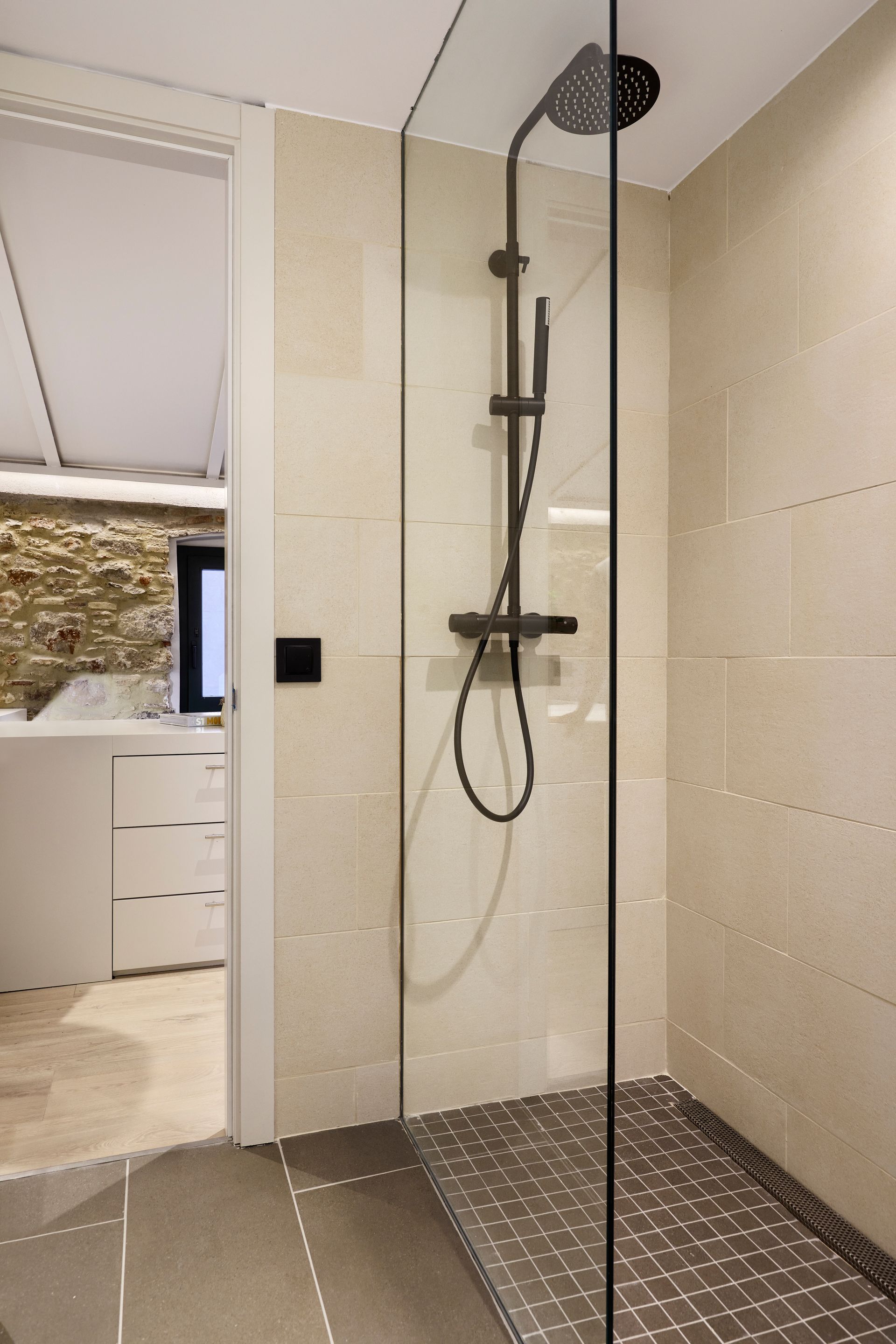 A bathroom with a walk in shower and a black shower head
