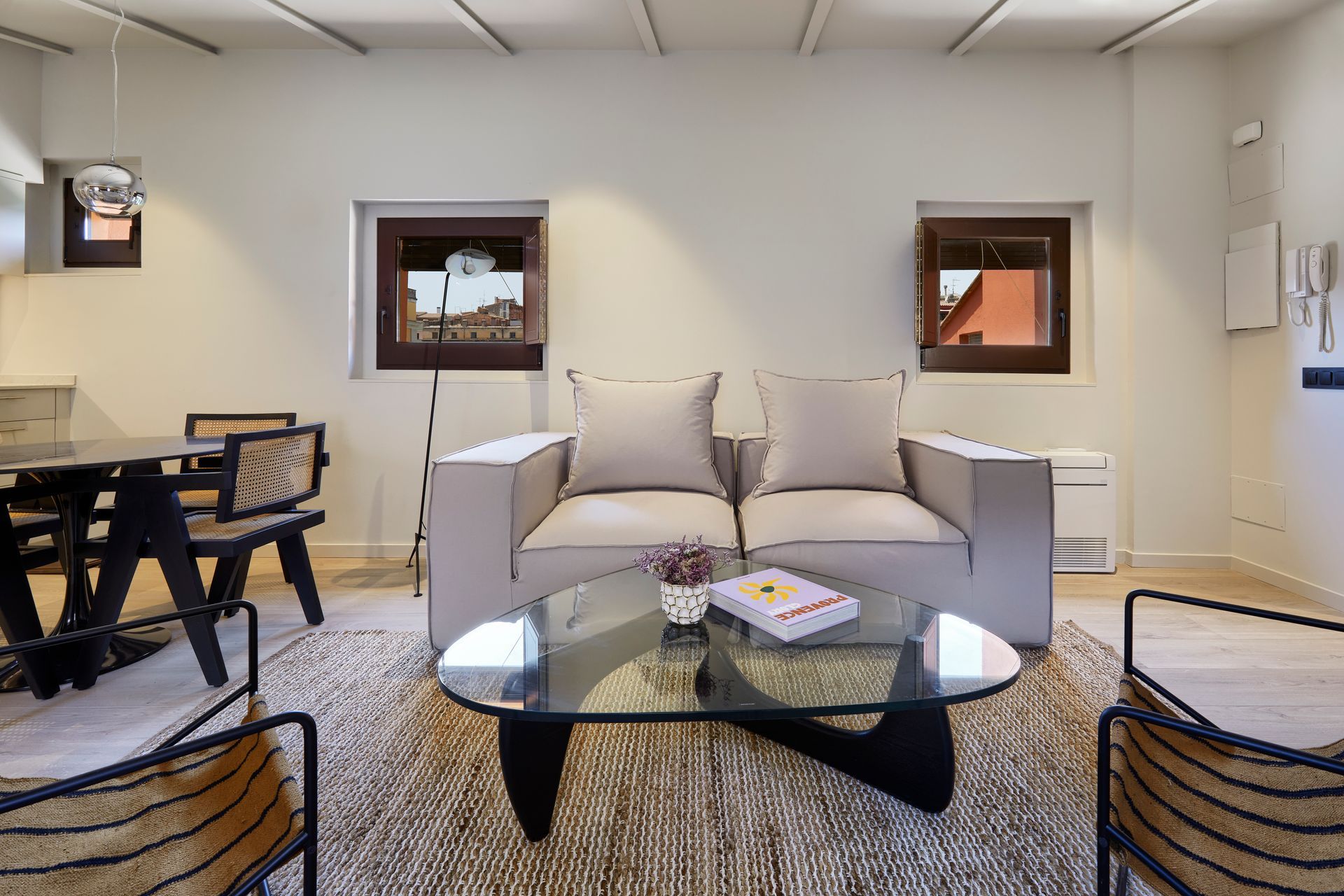 A living room with a couch , chairs , a table and a glass coffee table.