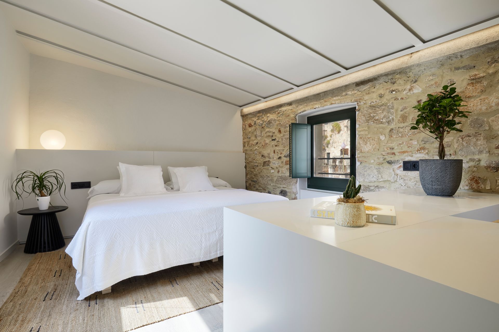 A bedroom with a large bed and a stone wall.