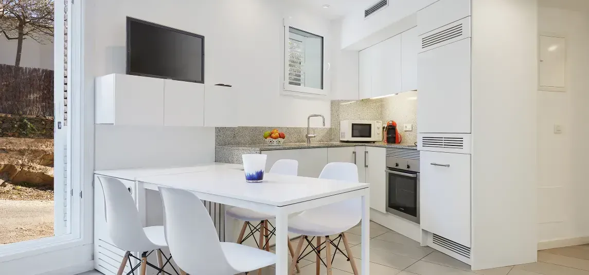A kitchen with a table and chairs and a flat screen tv.
