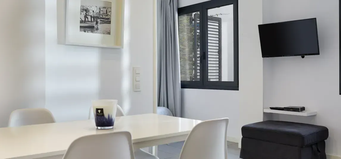 A living room with a table and chairs and a television.