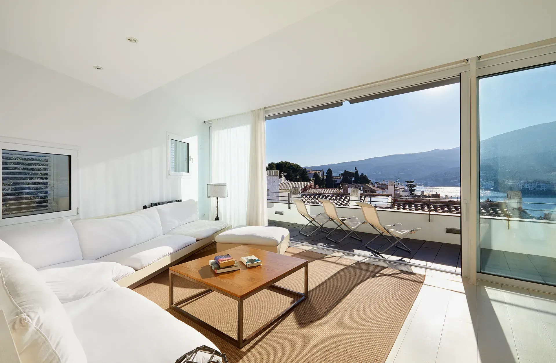 A living room with a couch , coffee table , chairs and a view of the ocean.