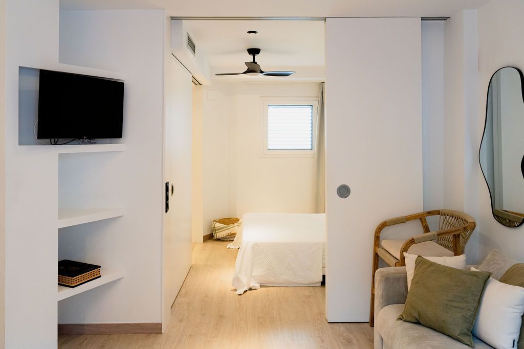 Bright hotel room interior with a bed, TV, and sliding door.