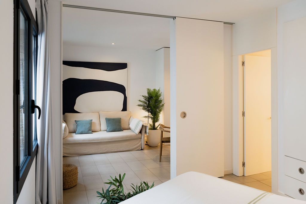 Interior view: white walls, sliding door open to sofa, art, window.
