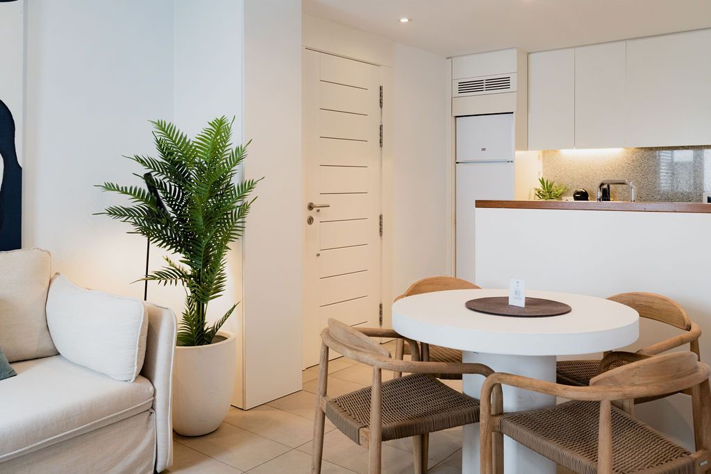 Bright, modern living space with white walls, a round dining table, and a potted plant.