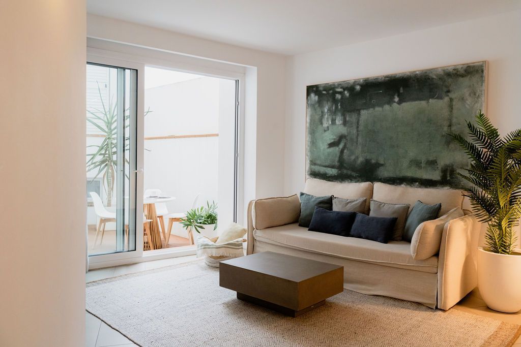 Living room with beige sofa, artwork, and sliding door to an outdoor patio.