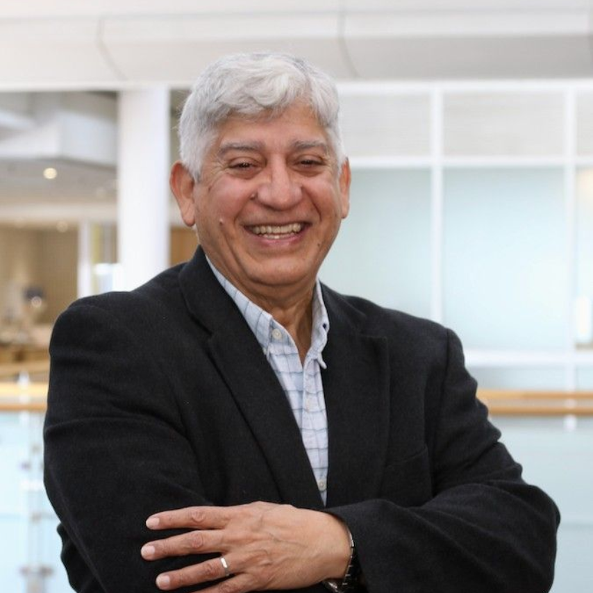 A man in a white shirt and red tie is smiling for the camera.