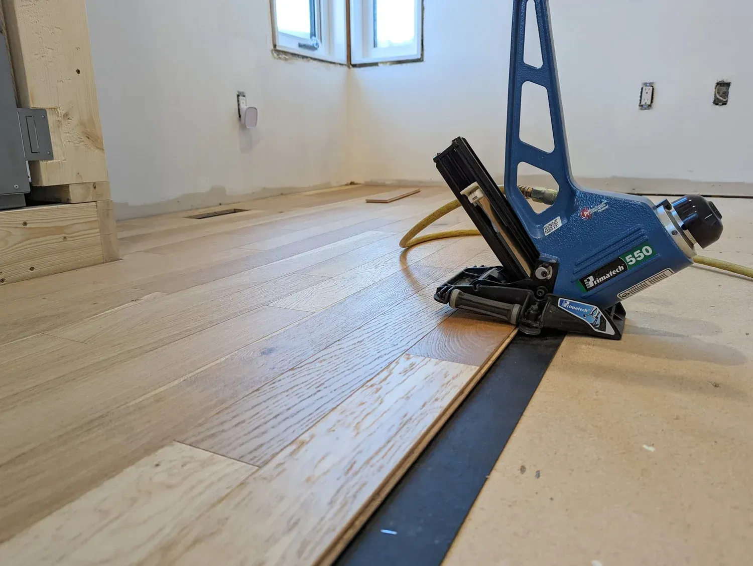 A floor nailer is used to install wooden flooring in a room.
