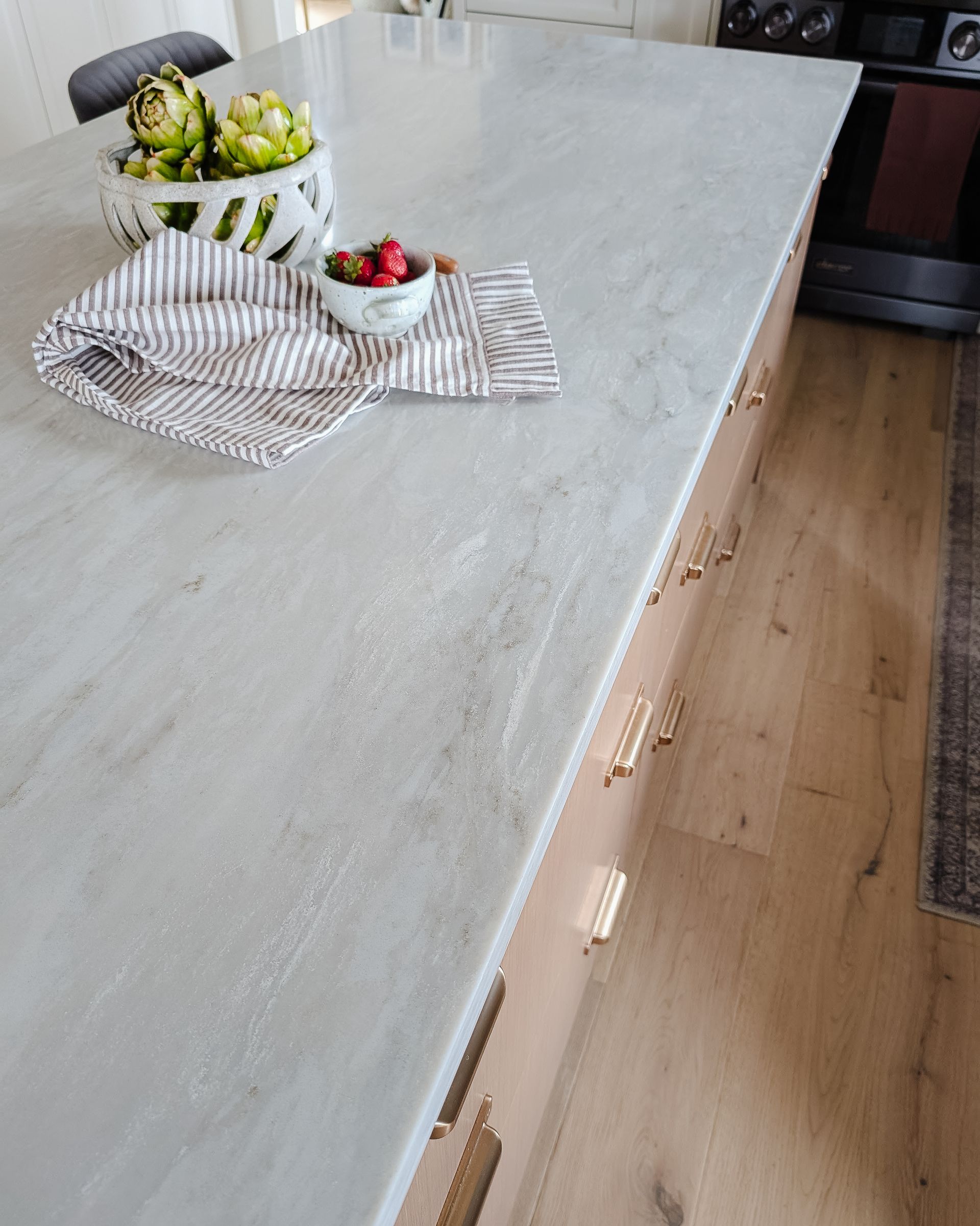 Kitchen island with light gray countertop, wooden cabinets, and decorative items.