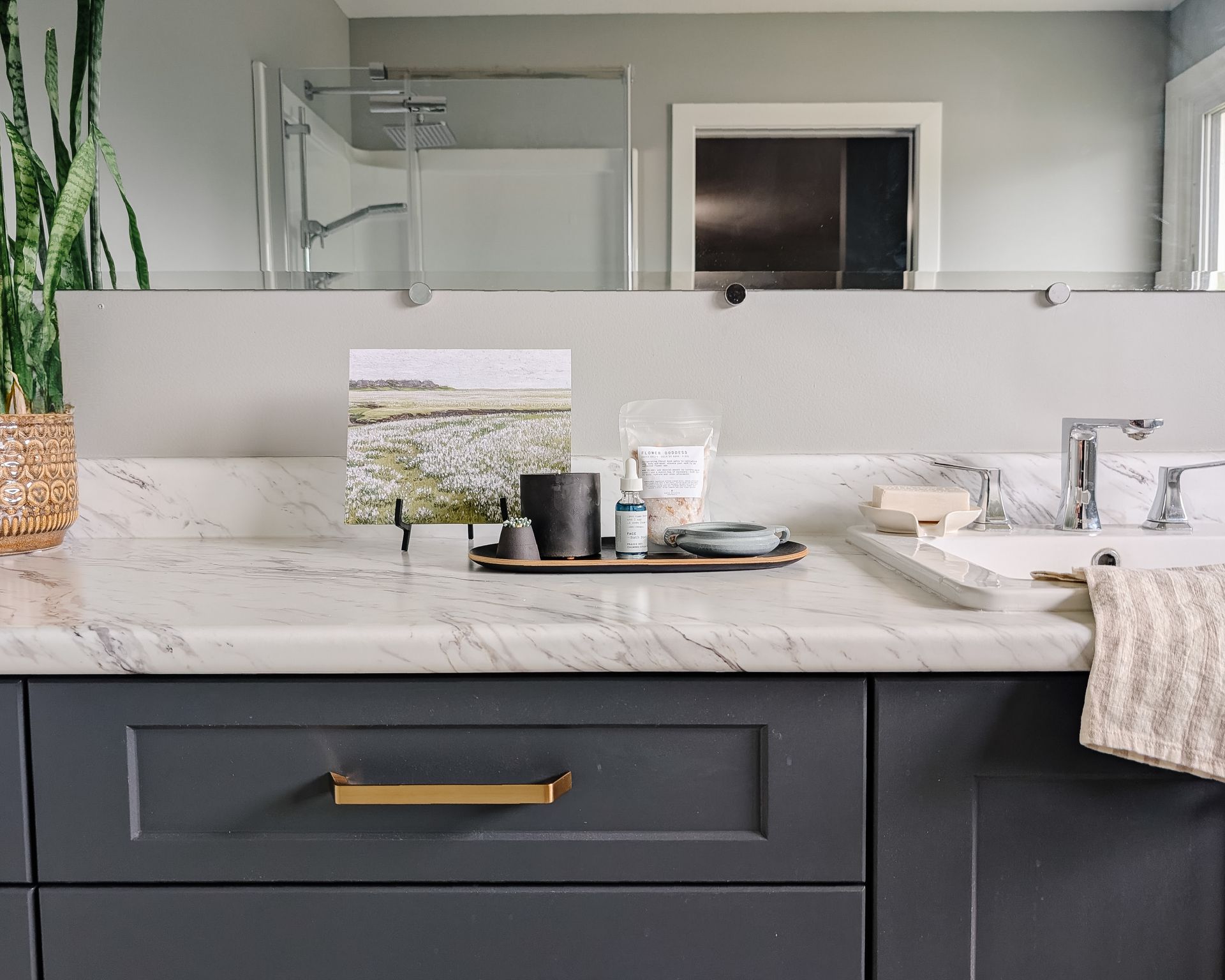 Bathroom with gray cabinets, white countertop, and decorative items.