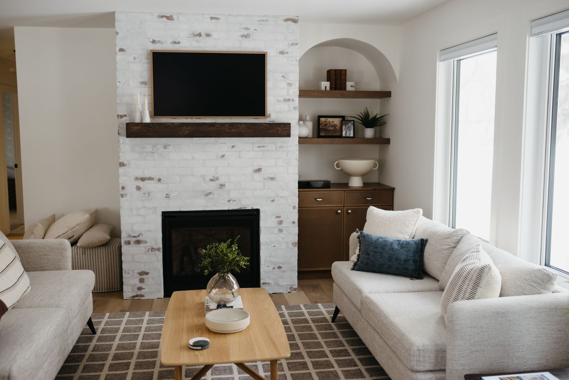 Living room with a fireplace, TV, built-in shelves, and two beige sofas.