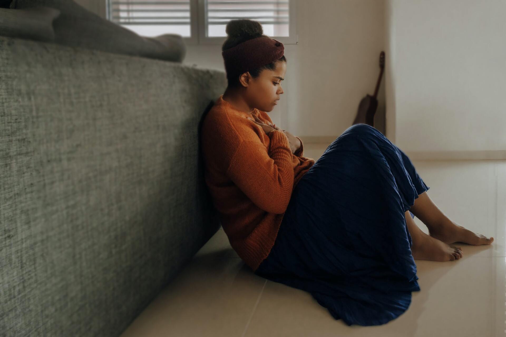 Woman sitting on the floor looking anxious. A Miami therapist shares tips to deal with panic attacks