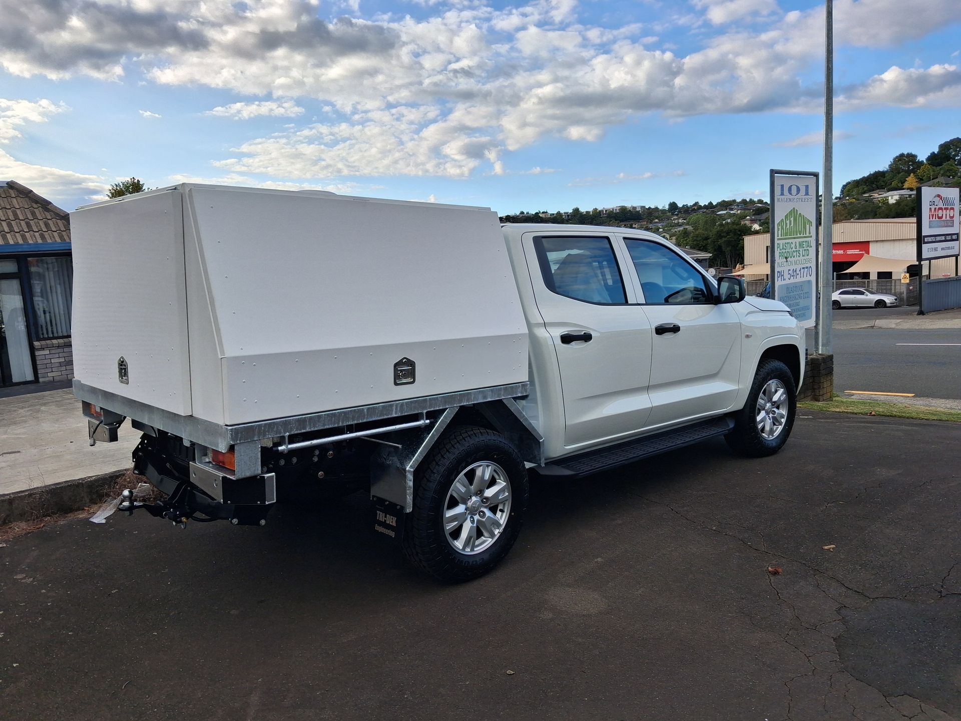 White dump truck with raised bed parked outside an industrial building