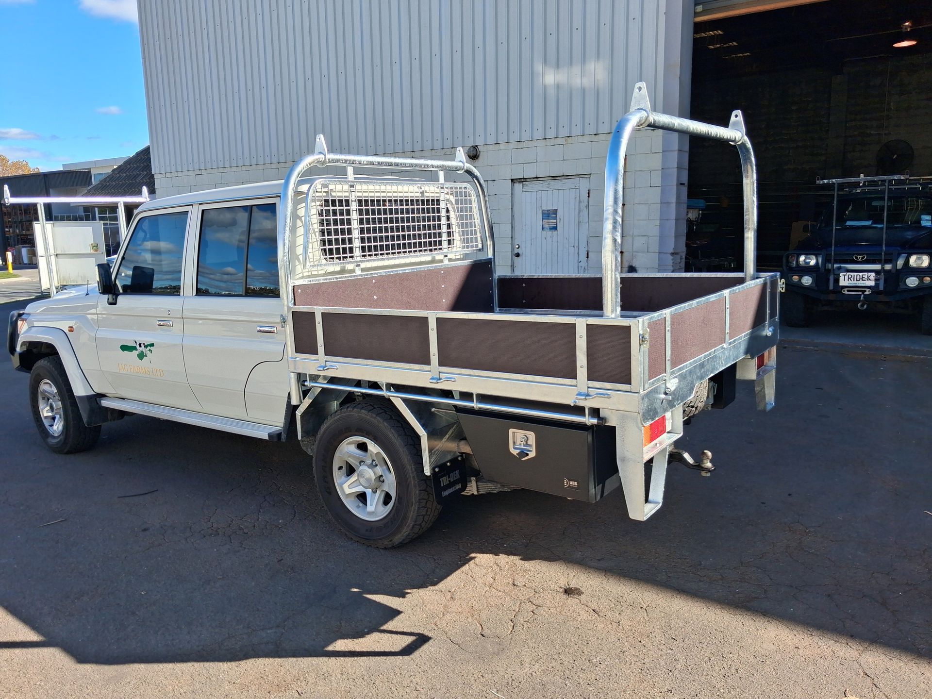 White utility truck with a covered cargo bed parked inside a warehouse or garage.