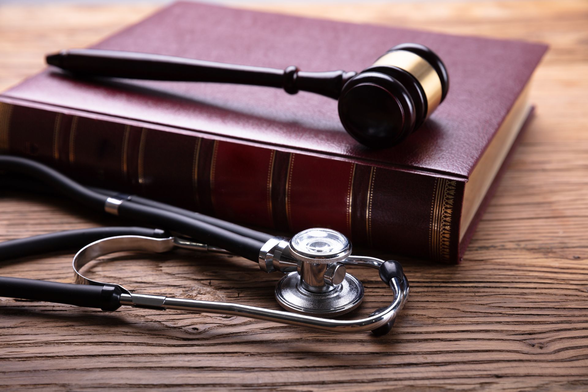 A gavel and stethoscope on a closed law book, wooden table.