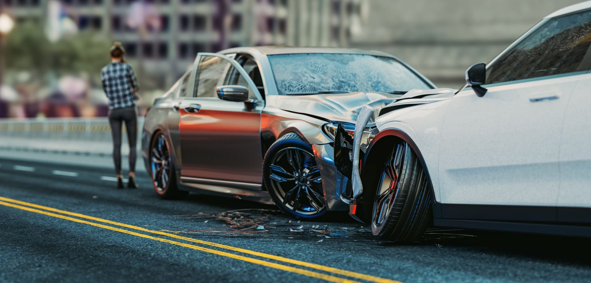 Two damaged cars stopped on a city street, with a person standing nearby and a wheel detached in front.