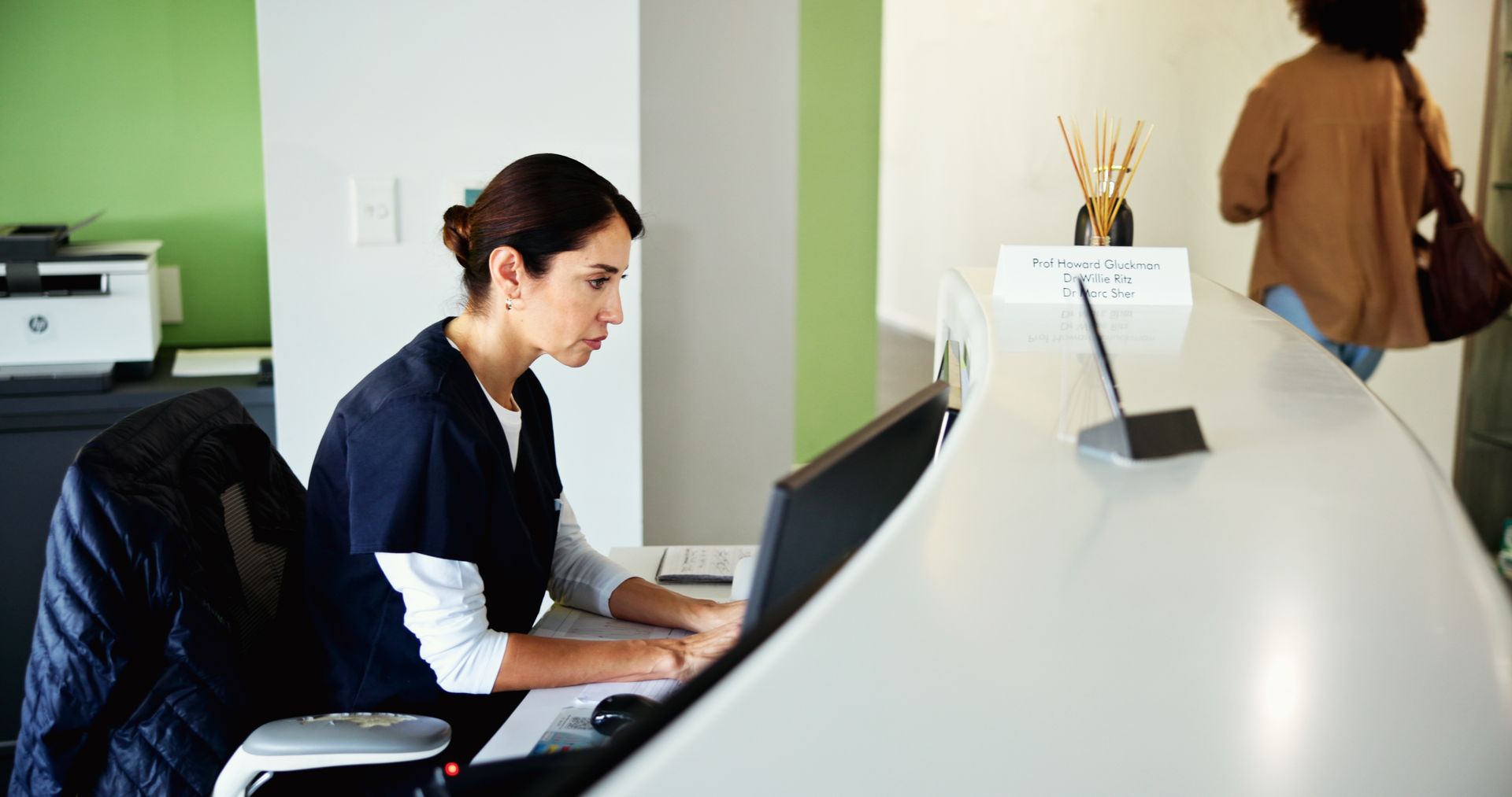 clinic-receptionist-and-woman-on-computer-for-med-2026-03-25-04-45-59-utc.jpg