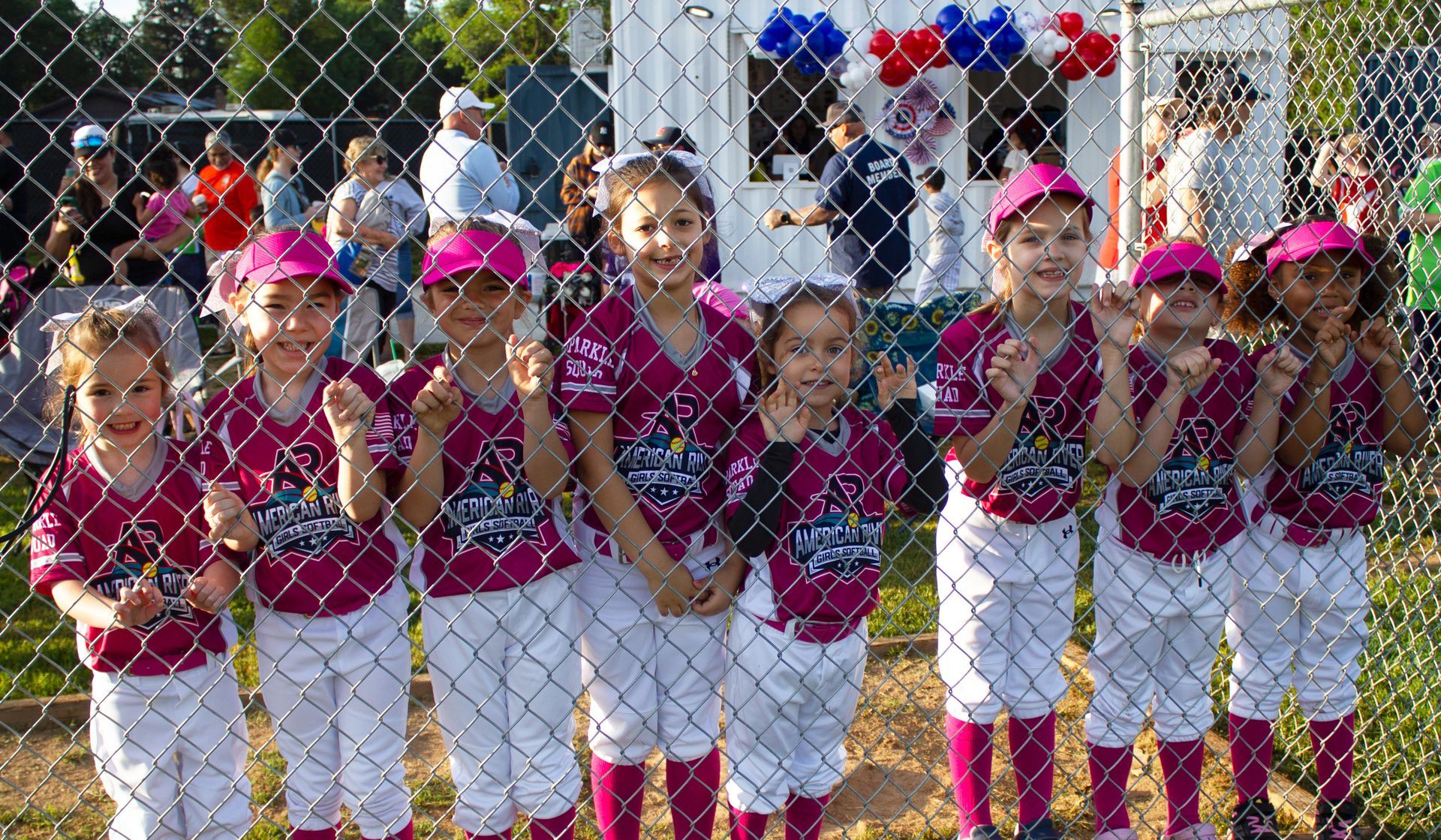 young softball players behind a dugout fence