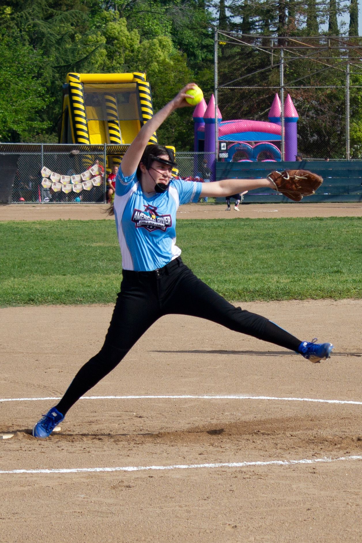 Softball player winding up to release a pitch