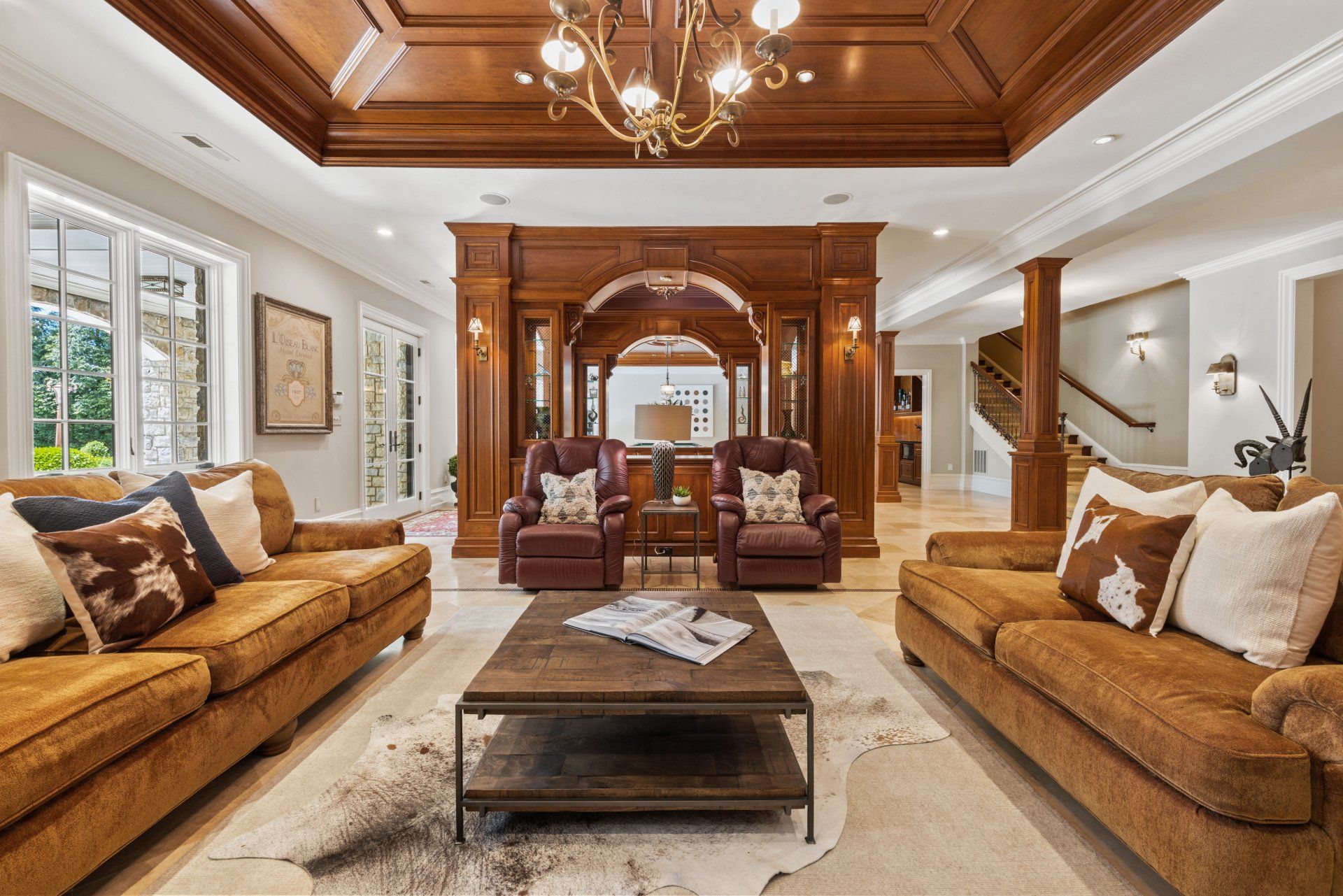 A luxurious living room with two couches , two chairs , a coffee table and a chandelier. Wood throughout including ceilings. Shoot by Craig Westerman. A luxurious living room with two couches , two chairs , a coffee table and a chandelier. Wood throughout including ceilings. Shoot by Craig Westerman.