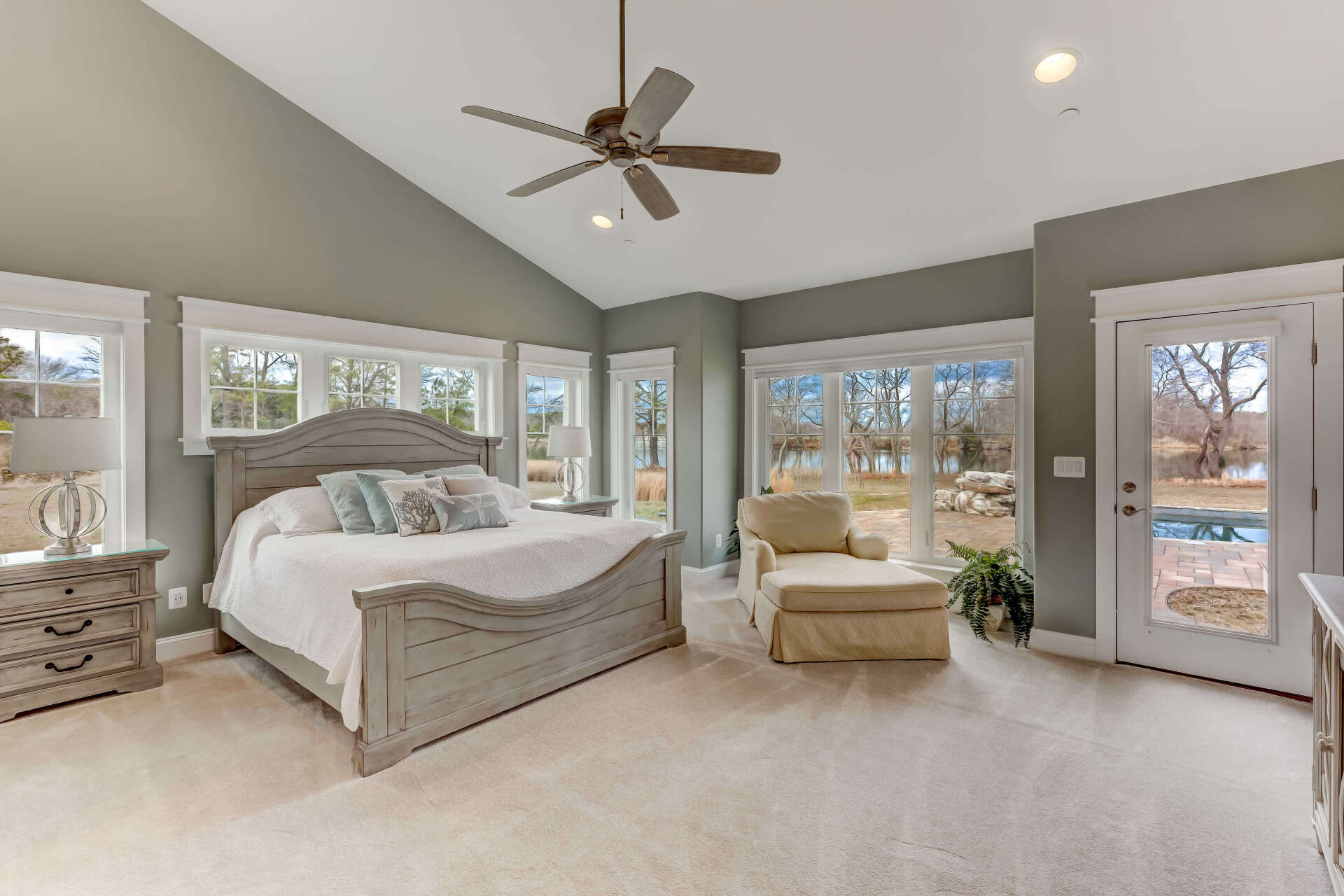 A bedroom with a bed , chair , nightstand and ceiling fan.