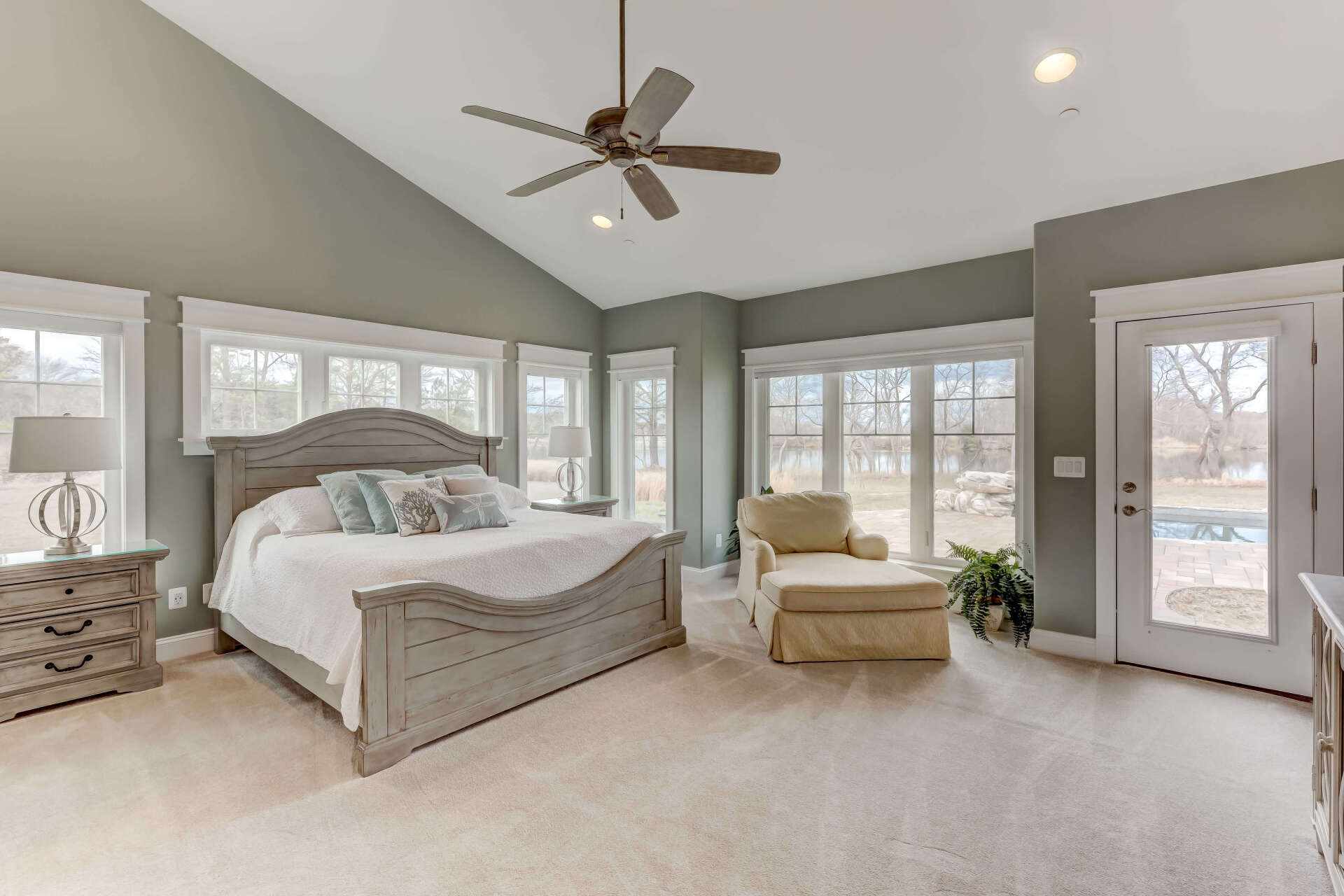 A bedroom with a bed , chair , nightstand and ceiling fan.