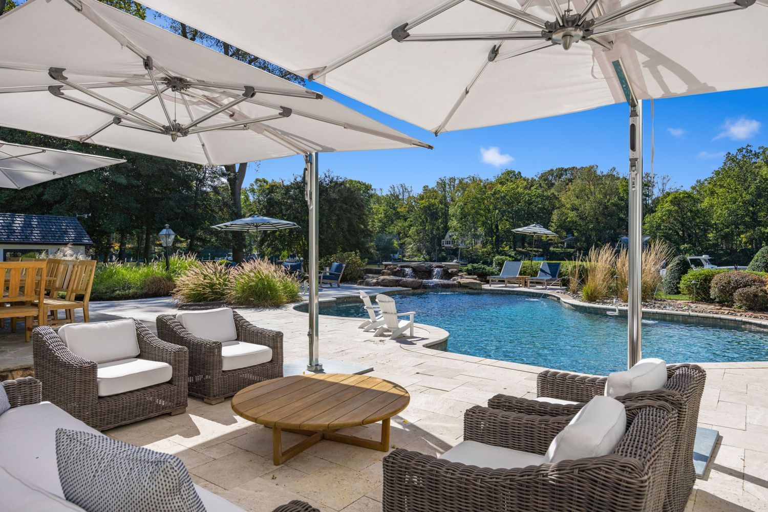 A patio with chairs and umbrellas next to a large swimming pool. Photo shoot by Craig Westerman