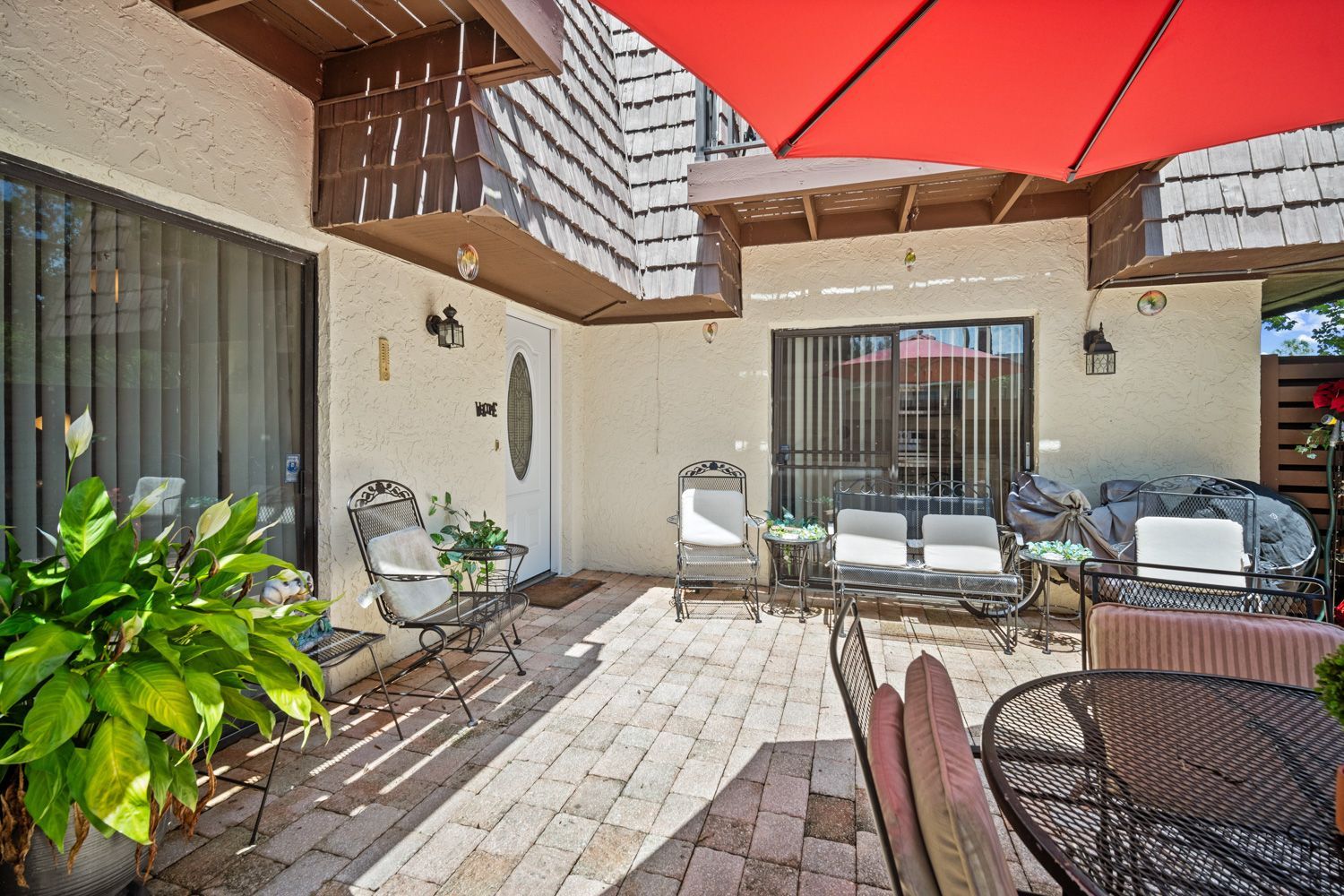 A patio with a red umbrella and a table and chairs in Tampa Florida by Craig Westerma