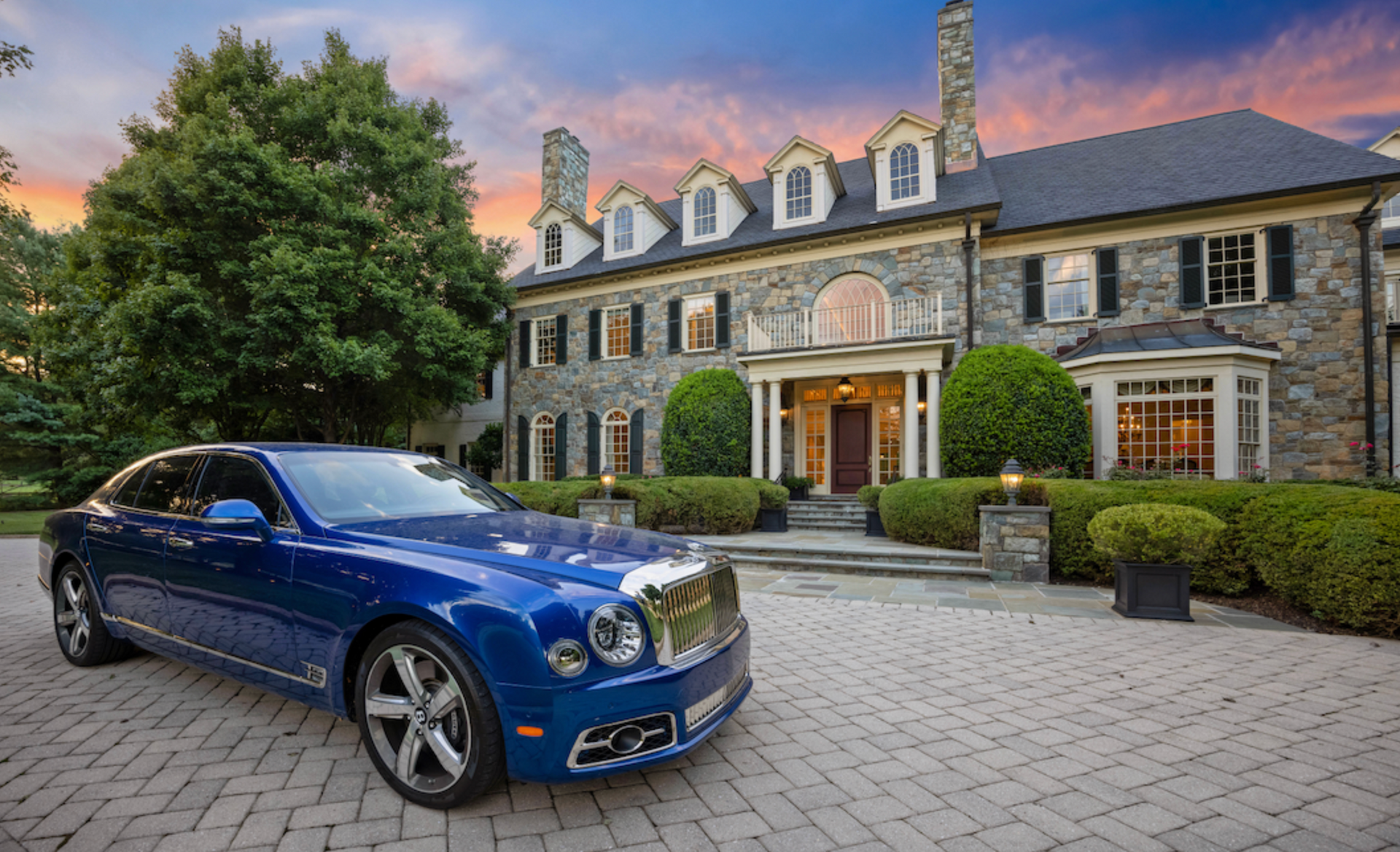 a blue luxury car is parked in front of a large stone house. photo by craig westerman a blue luxury car is parked in front of a large stone house. photo by craig westerman