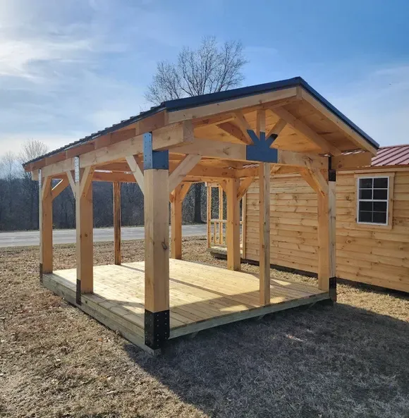 A wooden structure with a roof is sitting in the middle of a field.