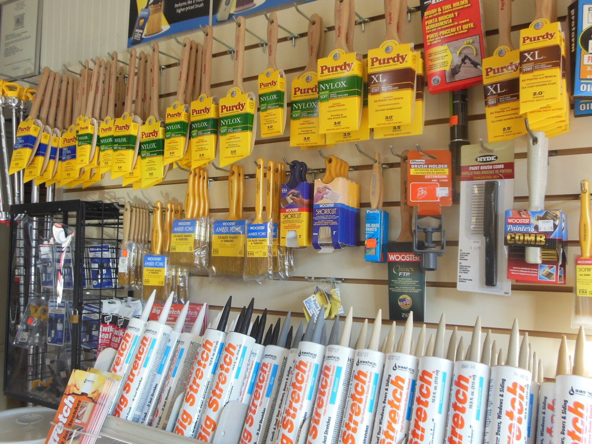 Paint brushes and caulk tubes displayed in a hardware store setting.