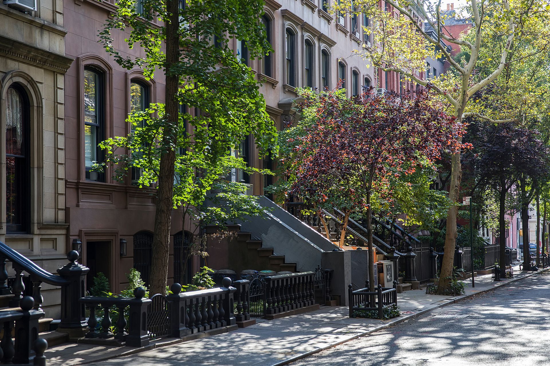 a row of houses on a city street with trees on the sidewalk