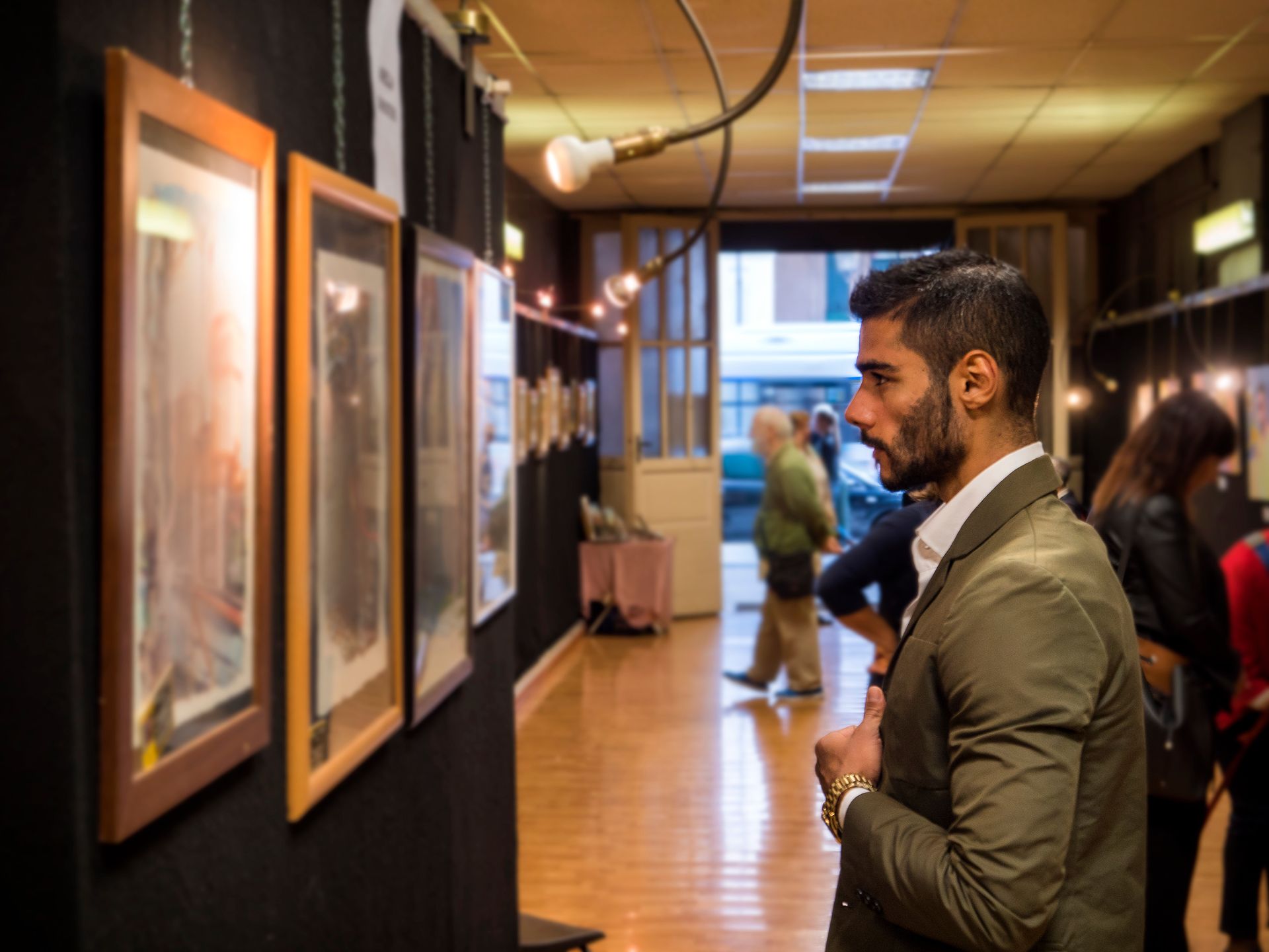A man in a suit is looking at a painting in an art gallery.